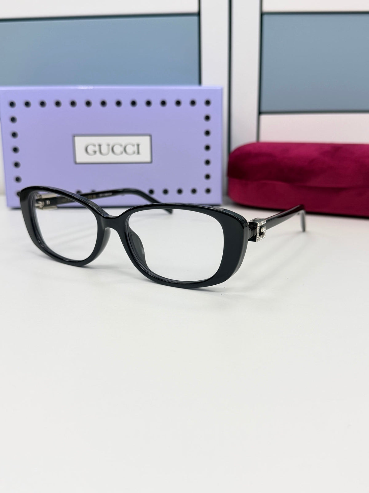 Black Gucci eyeglasses in a lilac box and red case