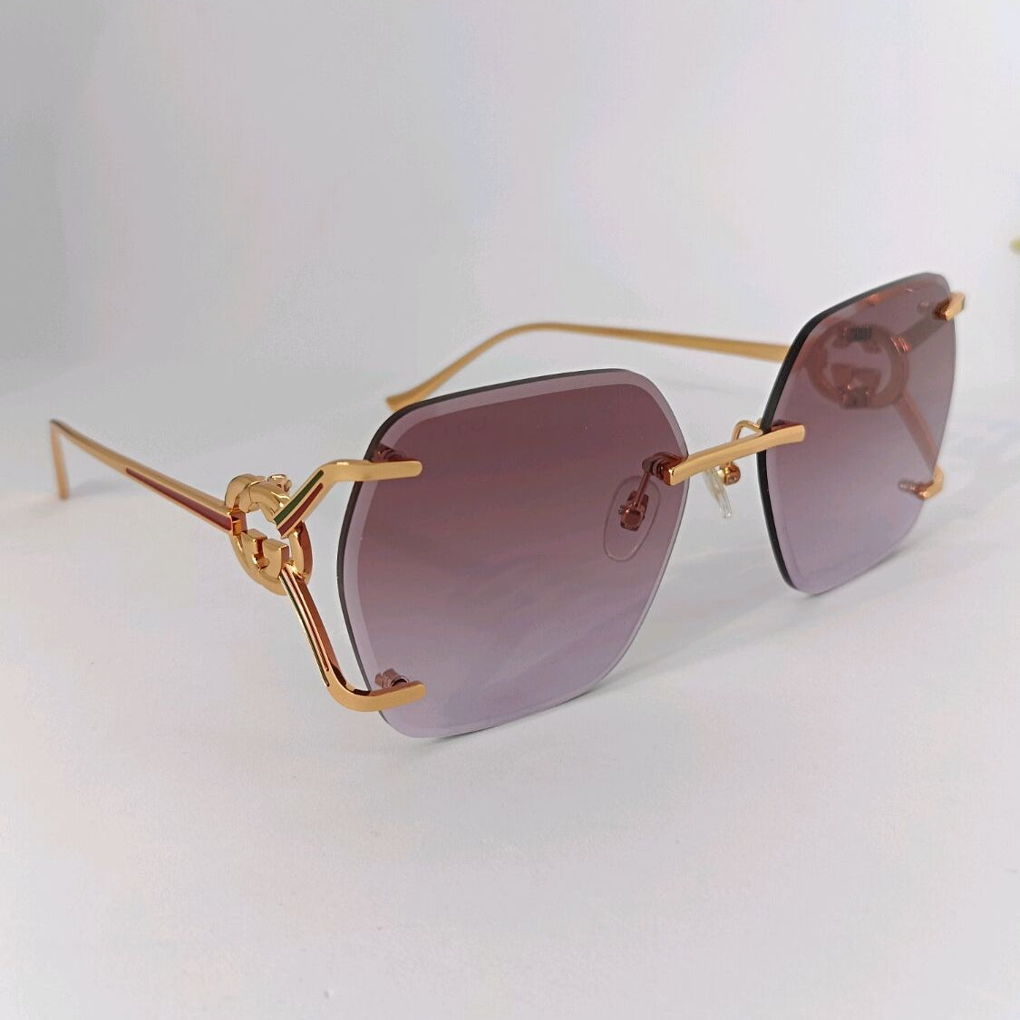 Gold-framed luxury sunglasses with purple gradient lenses and interlocking logo details.