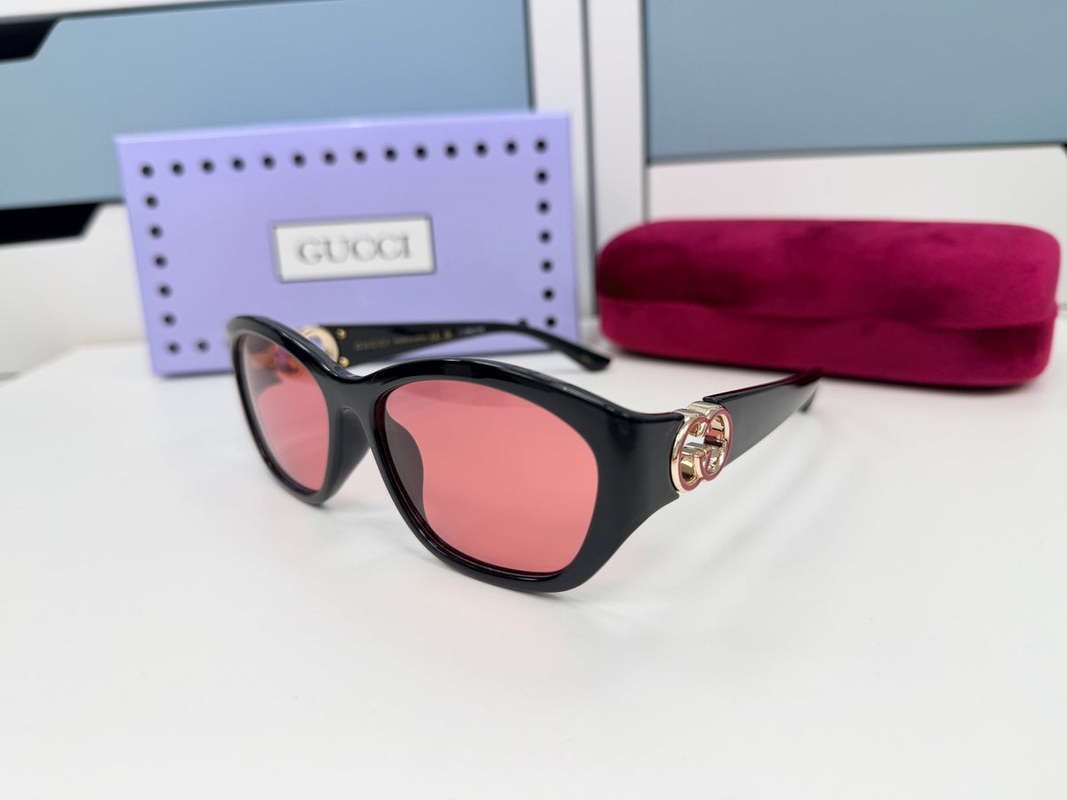 Gucci luxury sunglasses with red lenses and black frames, paired with a purple case and pink pouch.