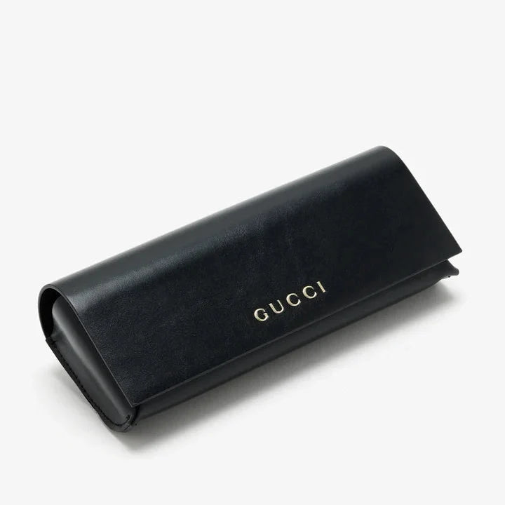 Black leather Gucci sunglasses case with gold logo lettering on a white background.
