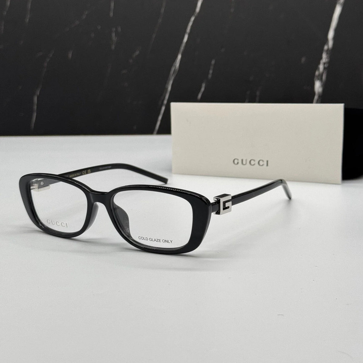 Black rectangular luxury eyeglasses with gold-tone metal accents on a white surface.